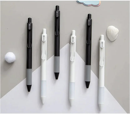 Set of black and white pens on a gray surface with decorative elements.