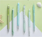 Set of six pens with different colored bodies on a green and white background