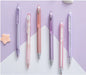 Set of six pens in various pastel colors on a light purple and white background