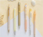Set of six pens with different designs and colors on a light background