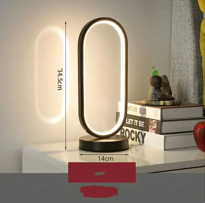 Modern LED table lamp on a white surface with books and decorative items in the background
